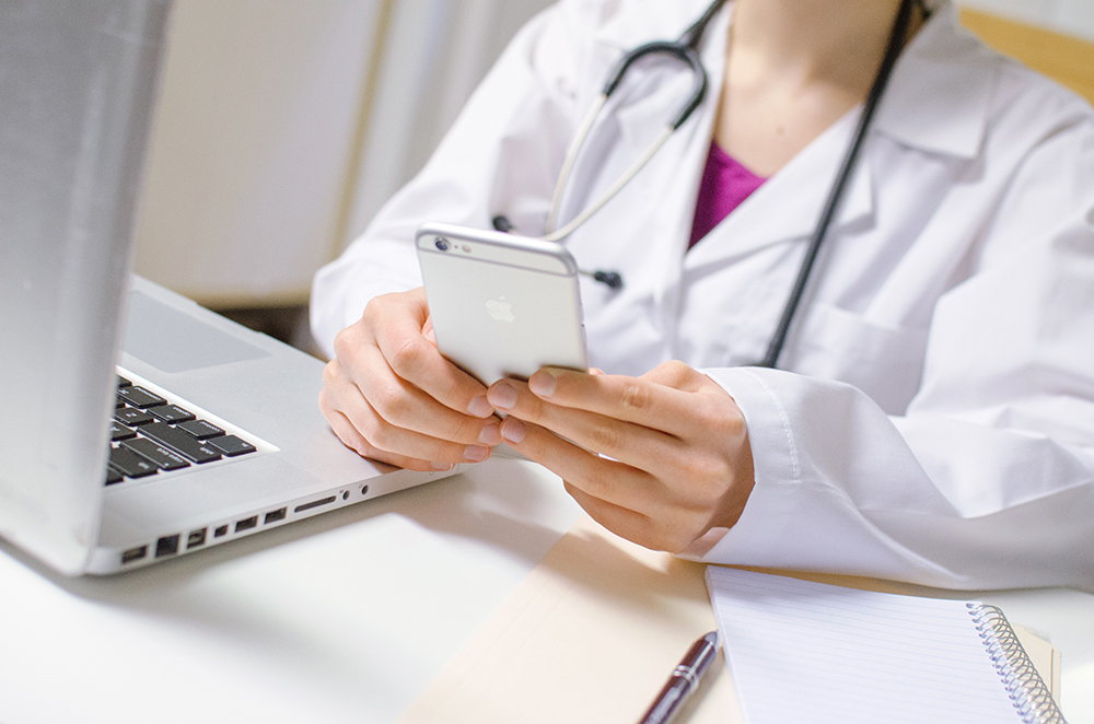 image of doctor using cell phone and laptop