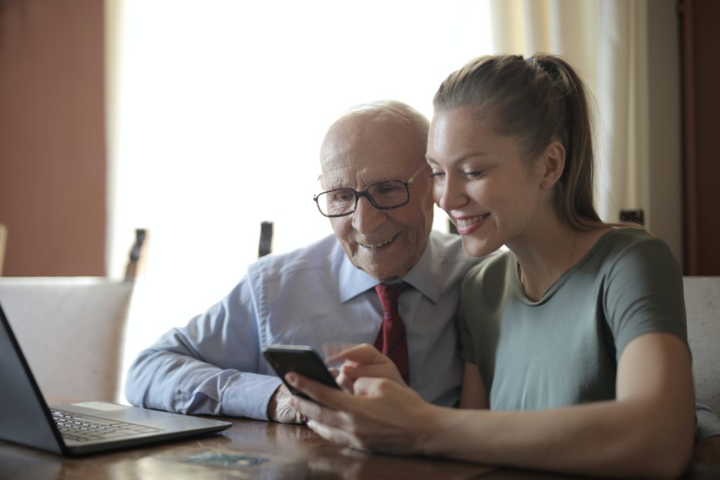 a woman and an elderly man looking at a mobile device