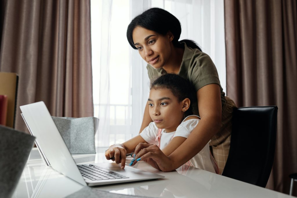 woman helping child on computer