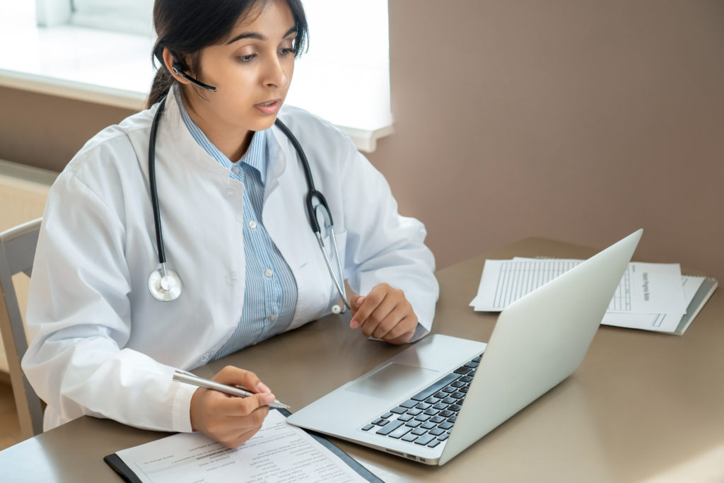 Telemedicine doctor wear headset talking to patient by online video call.